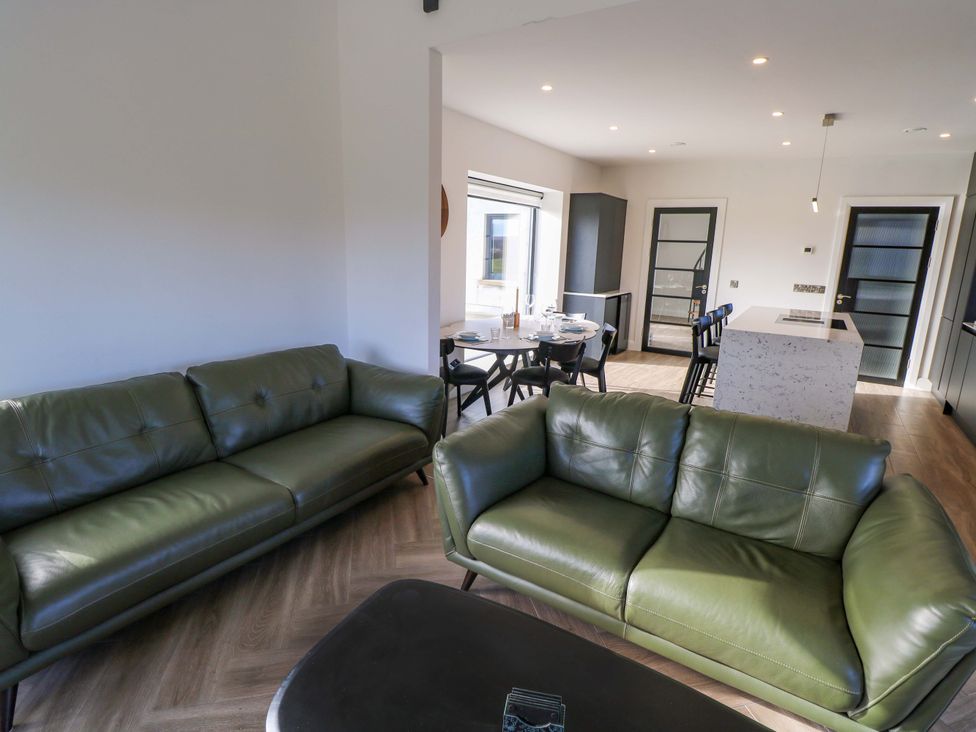 A living room with green sofas and a dining area at An Tobar in Ballina