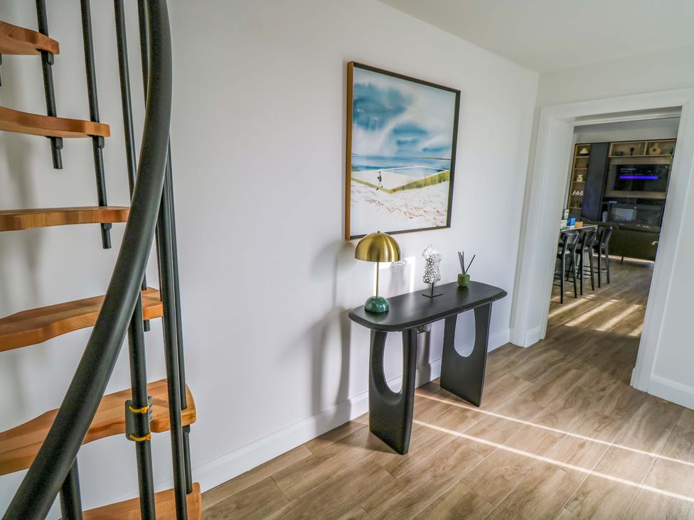 A hallway with a spiral staircase and a table with a lamp at An Tobar in Ballina