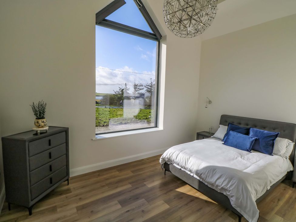 A bedroom with a bed and dresser at An Tobar, Ballina