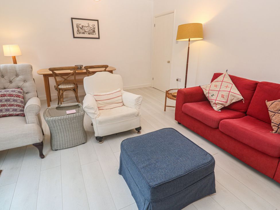 A living room with several seating options and a dining table at Pump Cottage in Truro