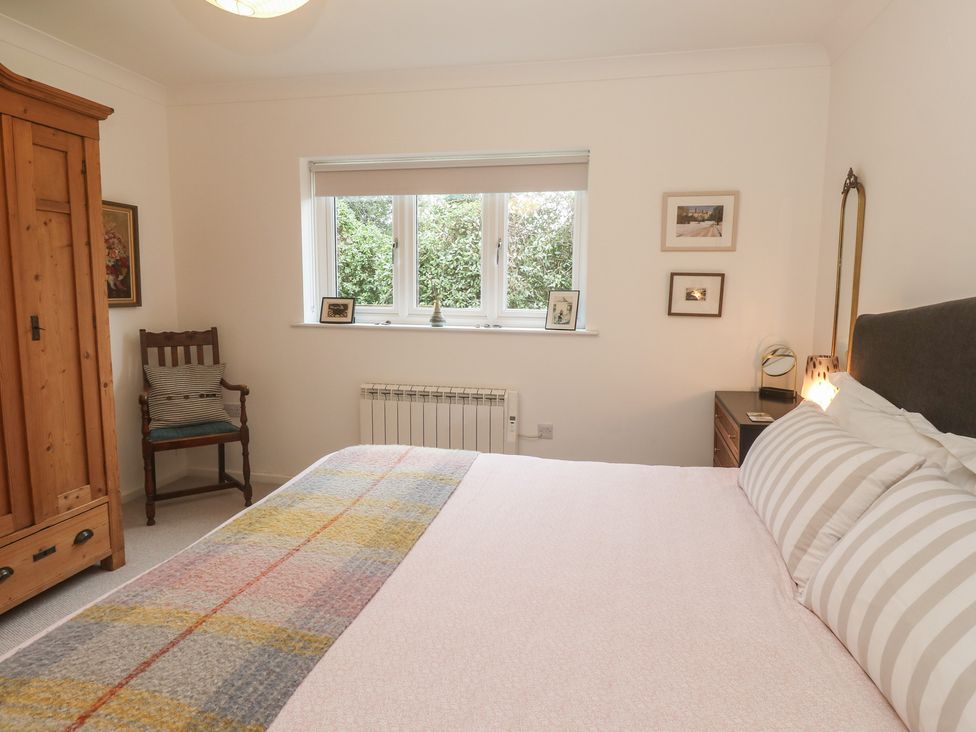 A bedroom with a bed, wardrobe, and window at Pump Cottage in Truro