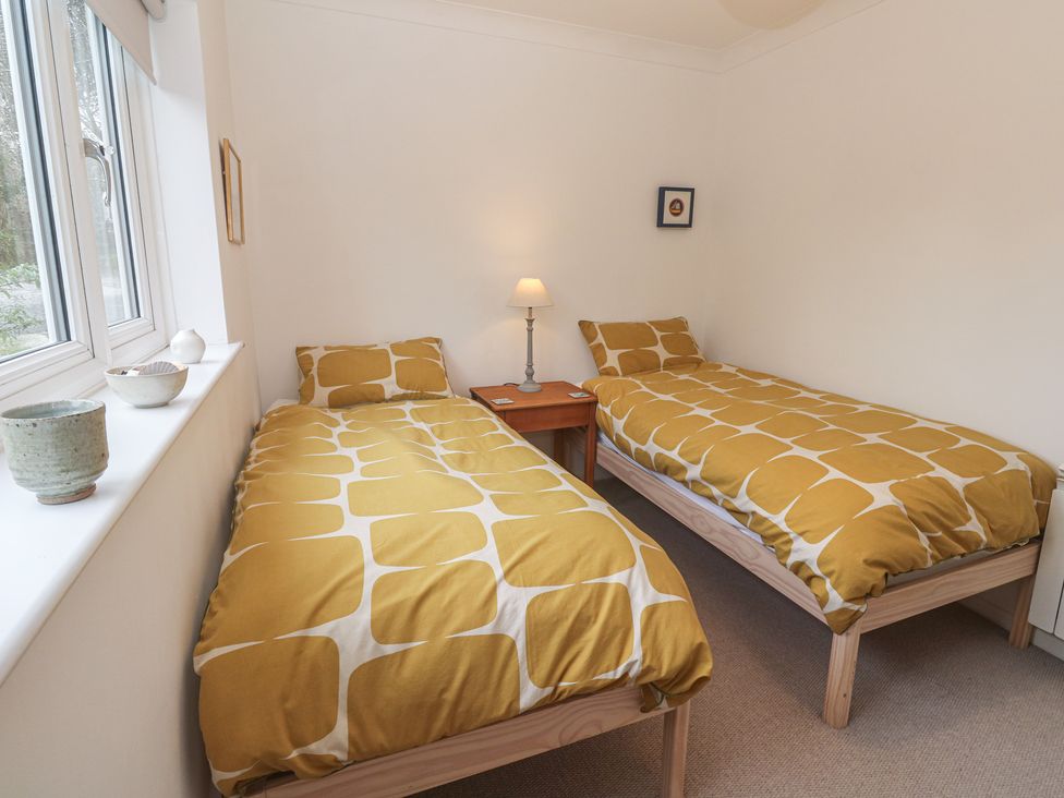 A bedroom with two beds and a lamp at Pump Cottage in Truro