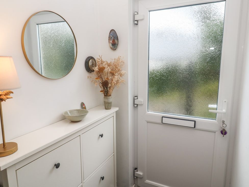 A hallway with a table, lamp and decorative items at Pump Cottage in Truro