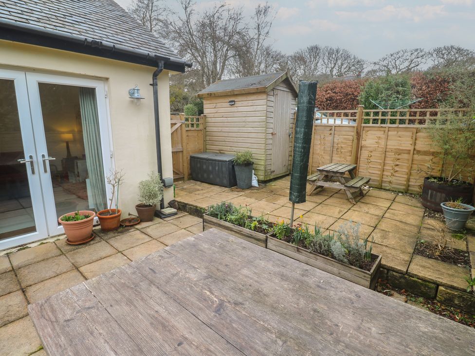 A patio with a table and bench at Pump Cottage in Truro