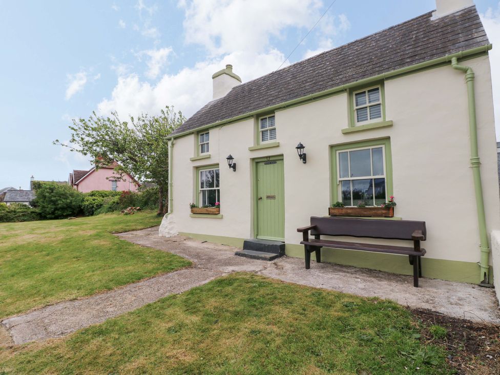 A cottage with a green door and bench at Beacon House in Marloes near Little Haven