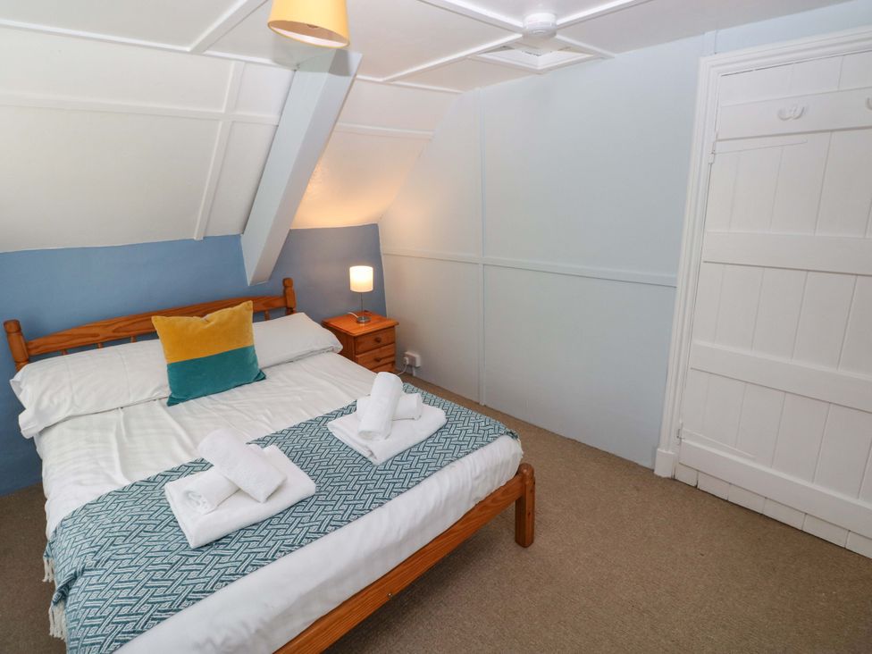 A bedroom with a wooden bed and nightstand at Beacon House in Marloes near Little Haven