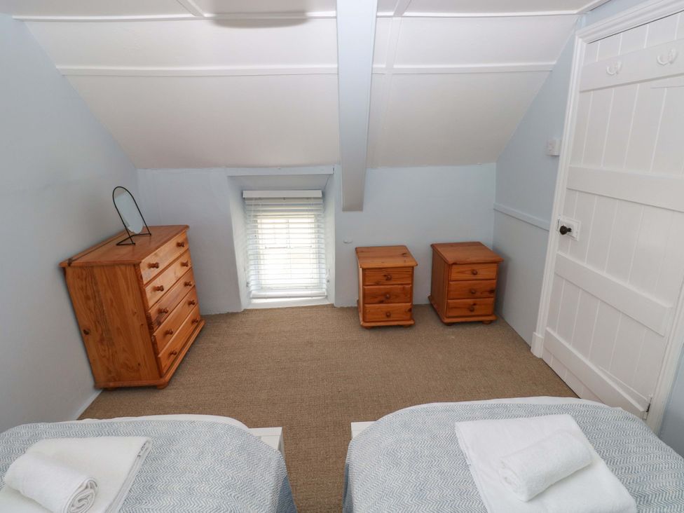 A bedroom with two beds and wooden furniture at Beacon House in Marloes near Little Haven