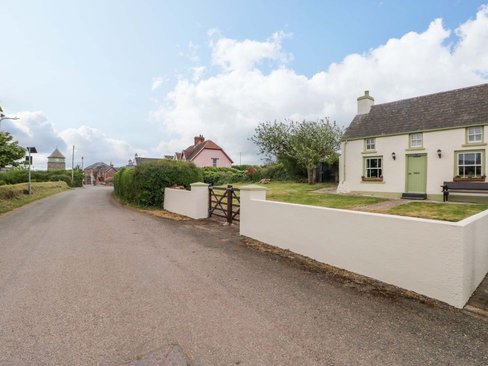 A house with a green door and fence on a road at Beacon House Marloes near Little Haven