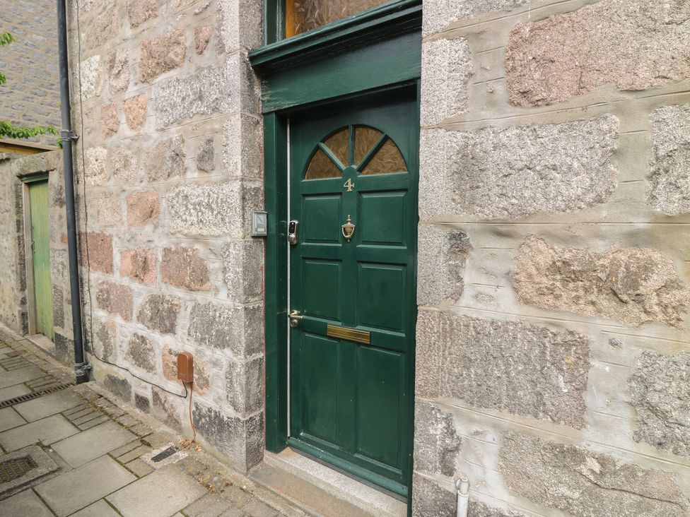 An entryway with a green door and stone wall at Pincerna Apartment Suite 1a in Aberdeen