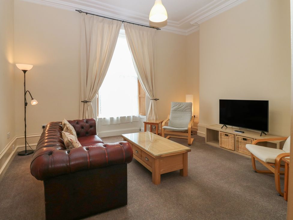 A living room with a sofa, coffee table, and television at Pincerna Apartment Suite 1a in Aberdeen