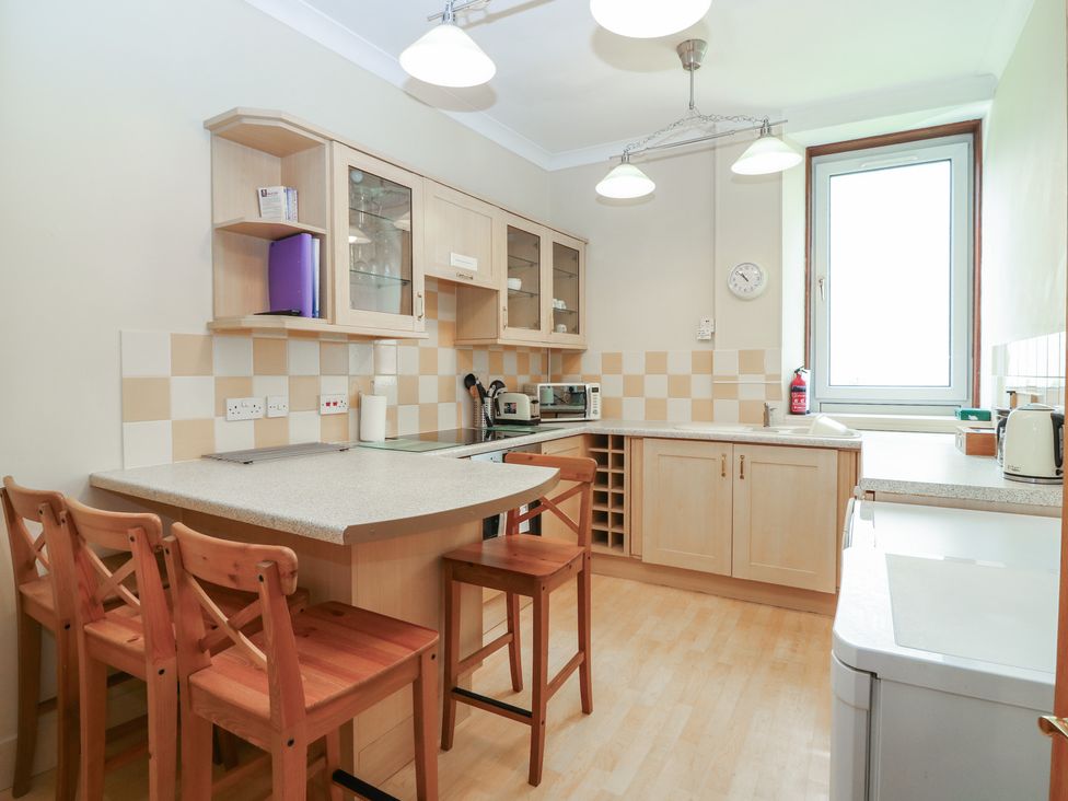 A kitchen with bar stools and cabinets at Pincerna Apartment Suite 1a Aberdeen