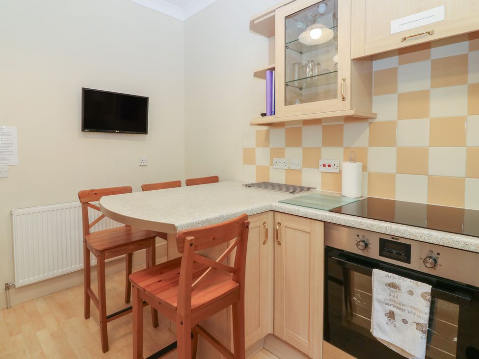 A kitchen with an oven and a table with chairs at Pincerna Apartment Suite 1a in Aberdeen