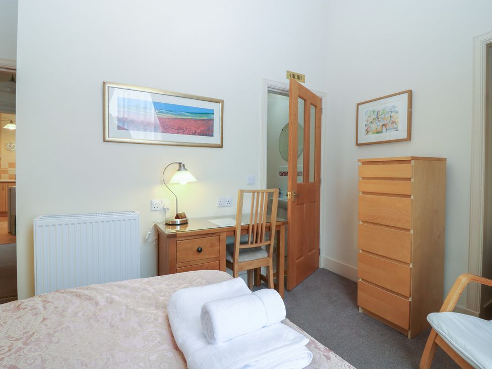 A bedroom with a bed, desk, chair, and dresser at Pincerna Apartment Suite 1a, Aberdeen