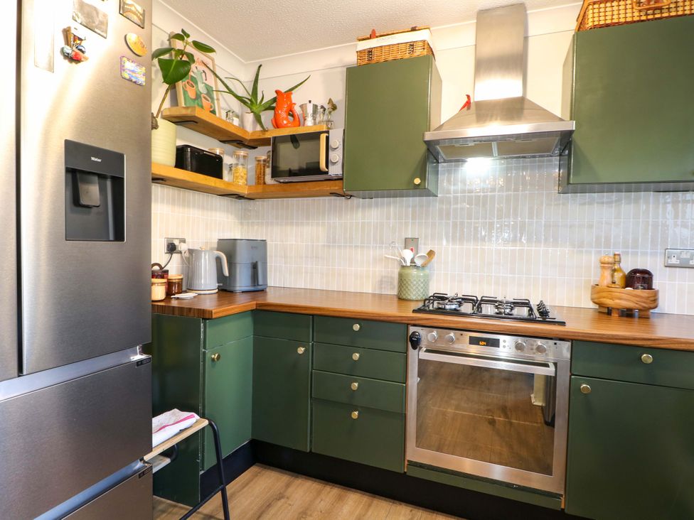 A kitchen with green cabinets and appliances at Flat 16 in Farnham