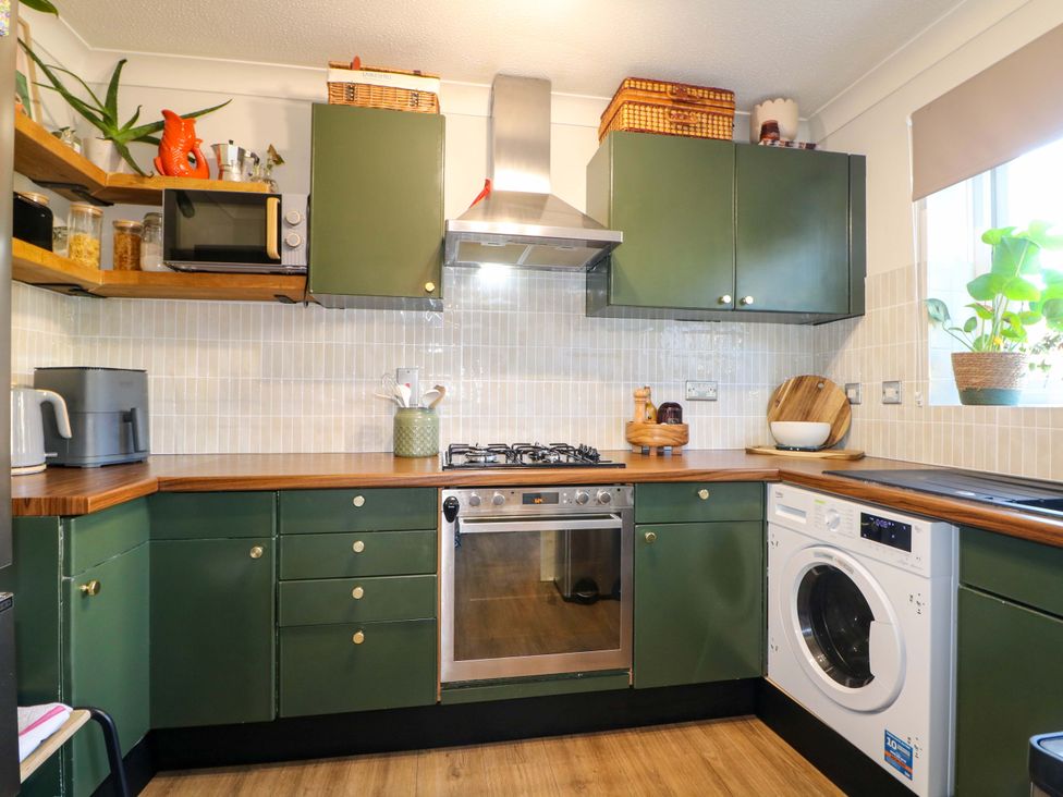 A kitchen with cabinets, cooking range, and washing machine at Flat 16 in Farnham