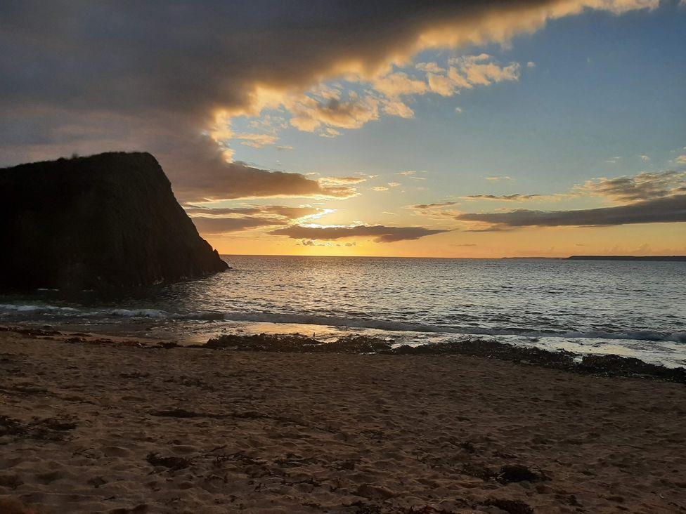 A beach with sand and waves at sunset at Hope Cove in Kingsbridge