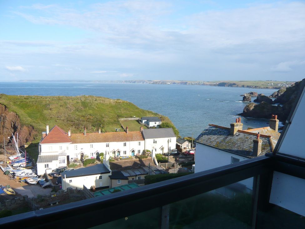 A view of the sea and coastline with buildings and boats at Hope Cove near Kingsbridge