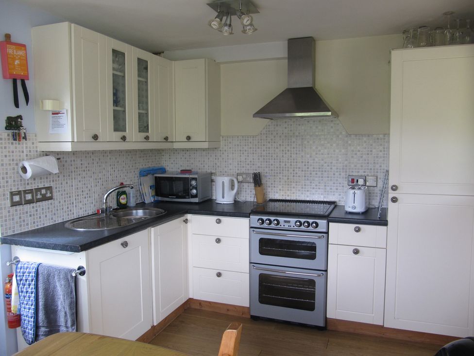 A kitchen with cabinets, sink, stove, and microwave at Hope Cove near Kingsbridge