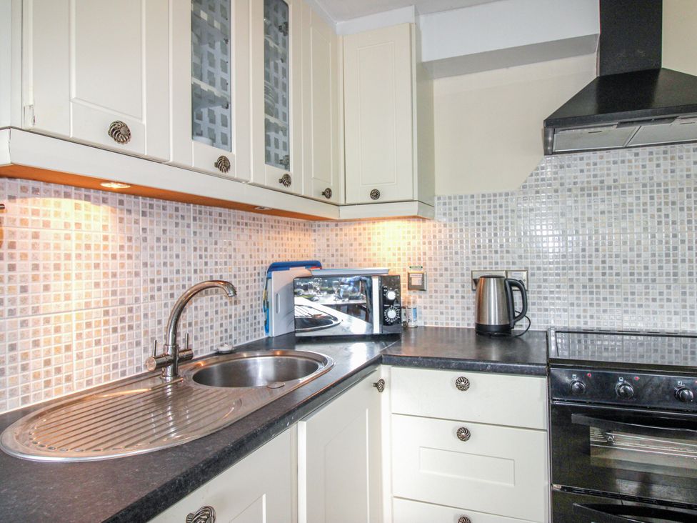 A kitchen with a sink, microwave, kettle, and stove at Quay Sands, Hope Cove