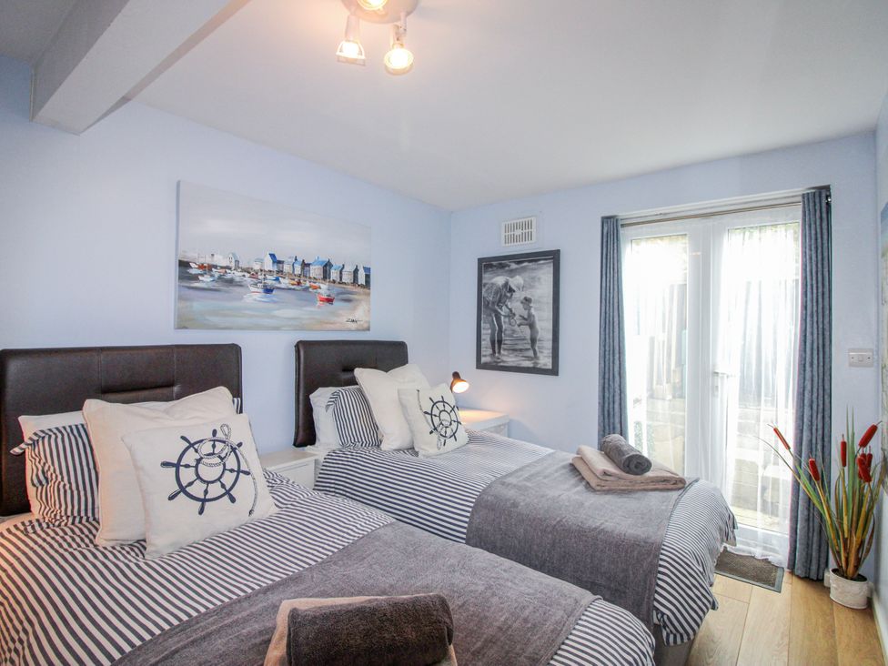 A bedroom with two single beds and a sliding door at Quay Sands, Hope Cove