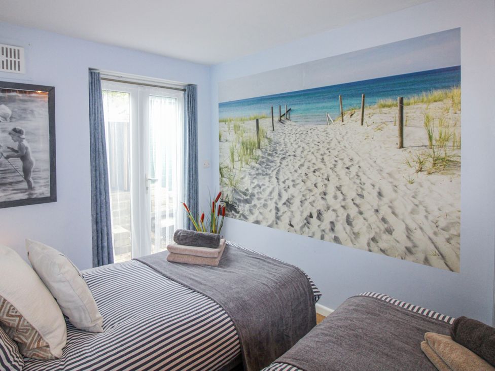 A bedroom with two beds and a beach mural at Quay Sands, Hope Cove