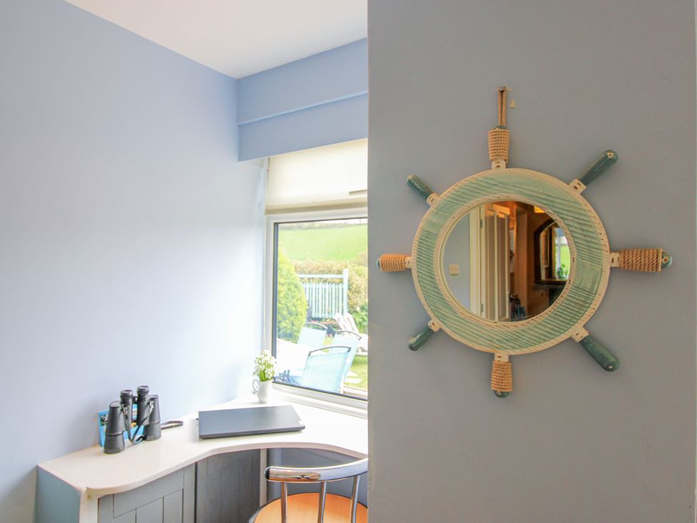 A desk with a laptop and a window at Quay Sands, Hope Cove