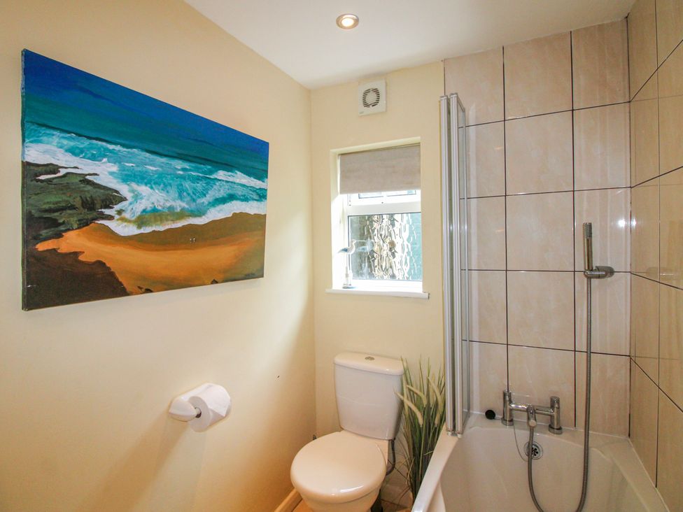 A bathroom with a bathtub and toilet at Quay Sands, Hope Cove