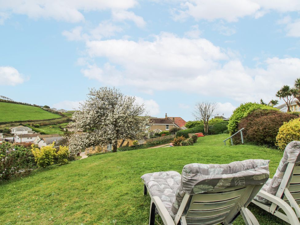 A garden with deck chairs and houses in the background at Quay Sands, Hope Cove