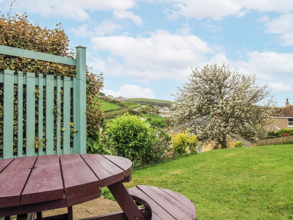 A garden with a wooden table and a tree at Quay Sands, Hope Cove
