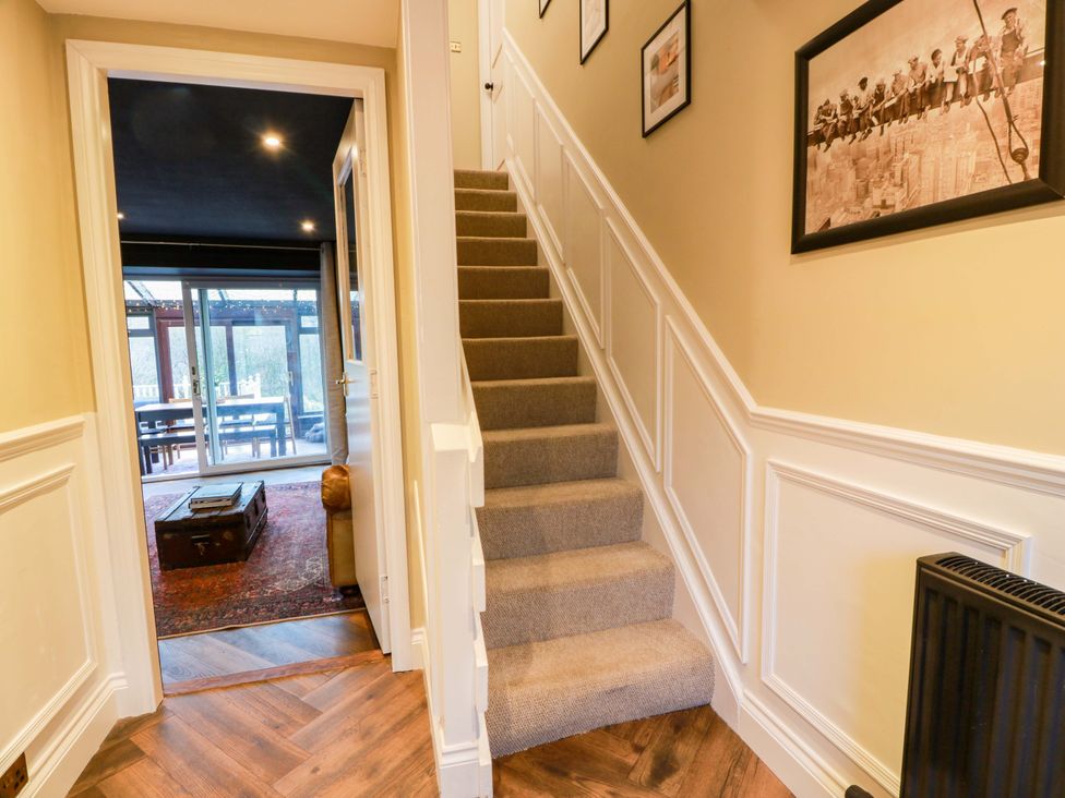 A hallway with a staircase and door leading to a conservatory at 7 Brewery Pool Newton Stewart