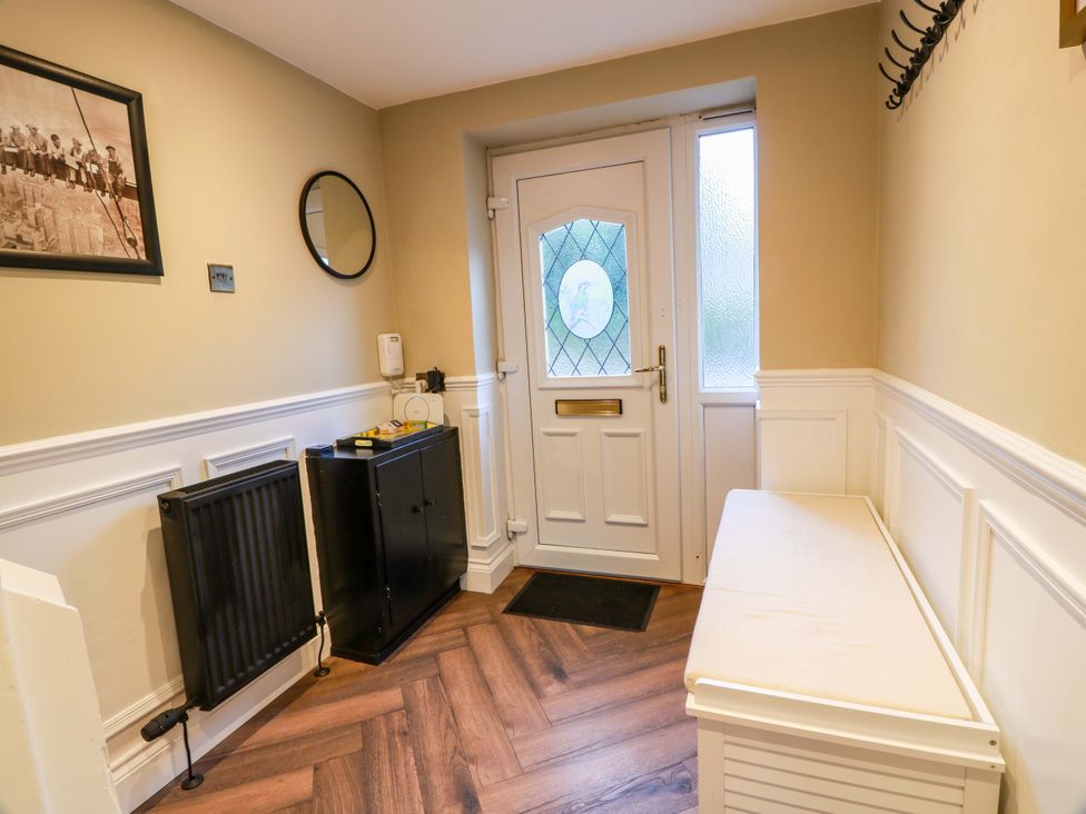 A hallway with a door, mirror, radiator, and bench at 7 Brewery Pool in Newton Stewart