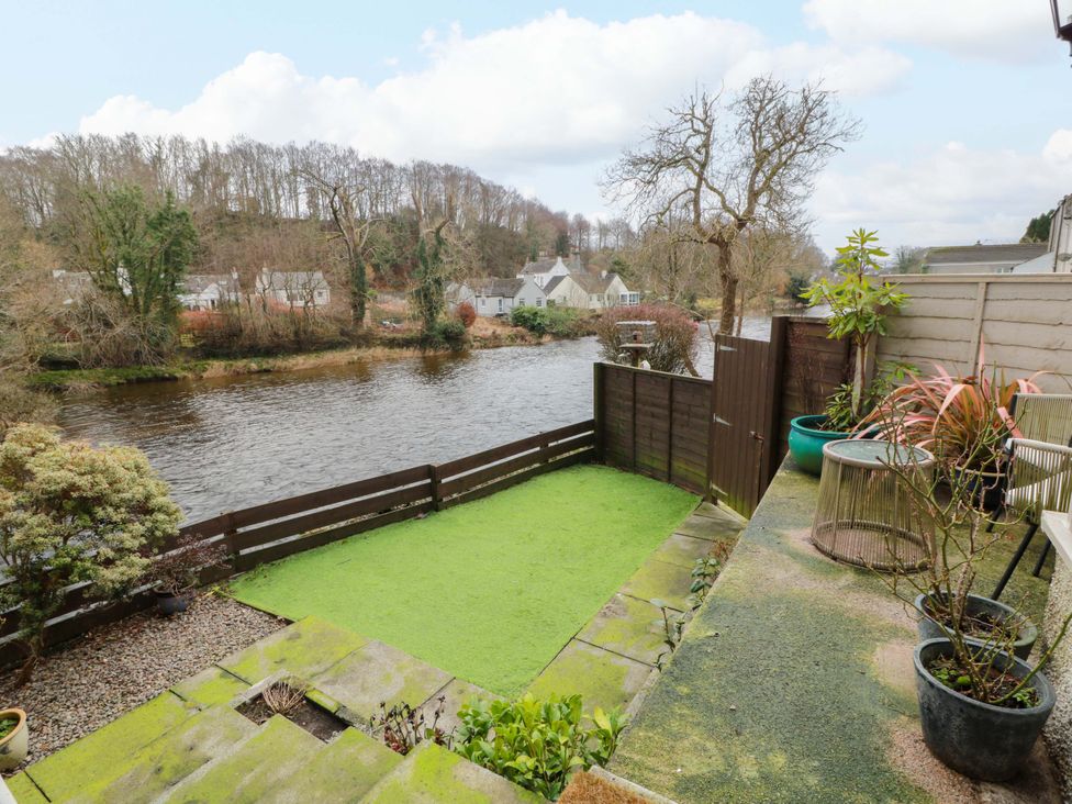A garden with a river view and pathway at 7 Brewery Pool in Newton Stewart