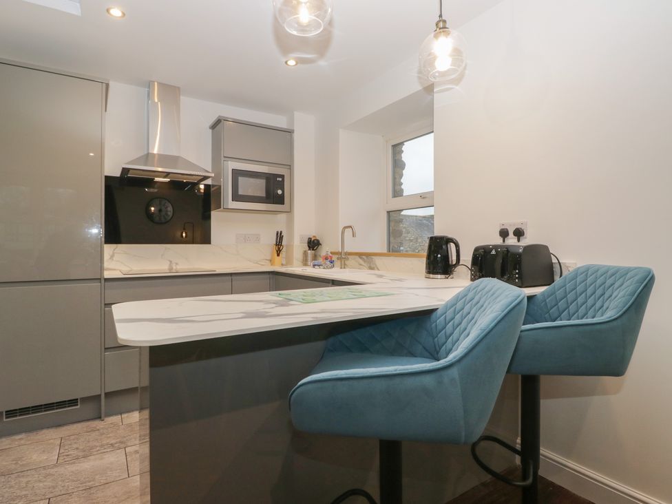 A kitchen with bar stools and appliances at 6 Hallin Fell in Penrith