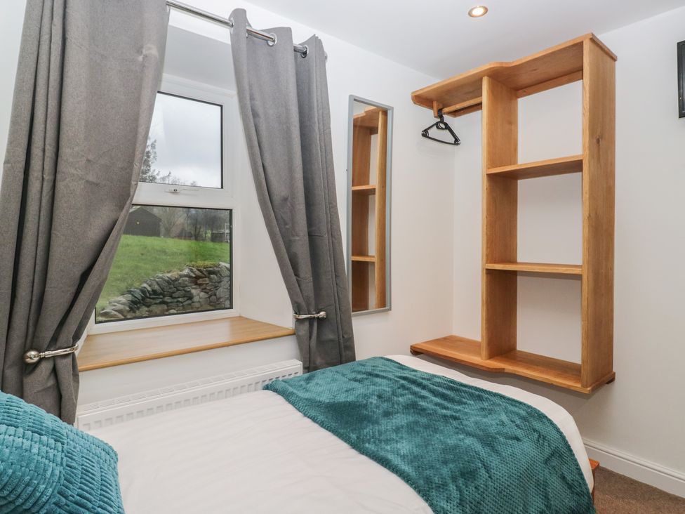 A bedroom with a bed, shelves and window at 6 Hallin Fell in Penrith
