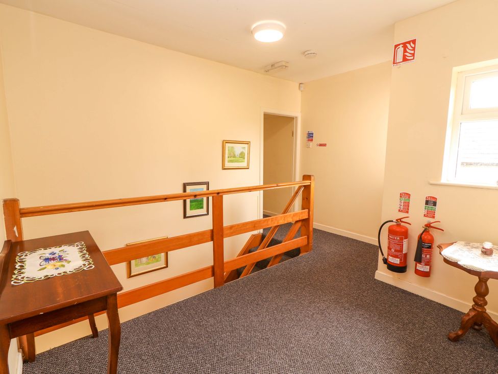 A hallway with a staircase and fire extinguishers at Macmathuna in Kilrush, County Clare