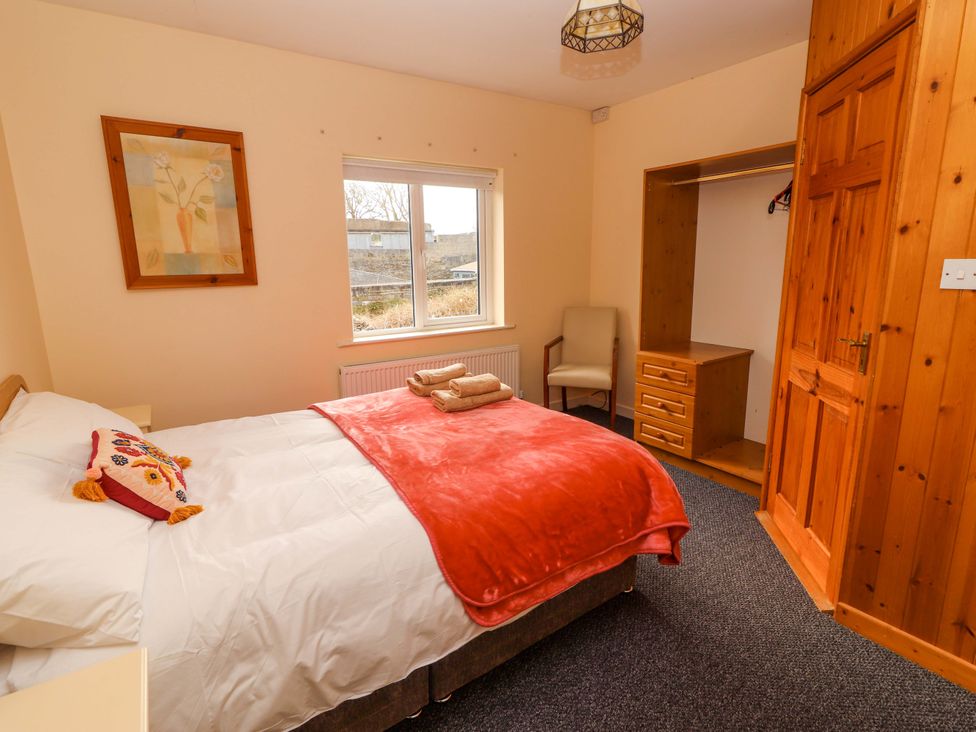 A bedroom with a bed and wardrobe at Macmathuna in Kilrush, County Clare