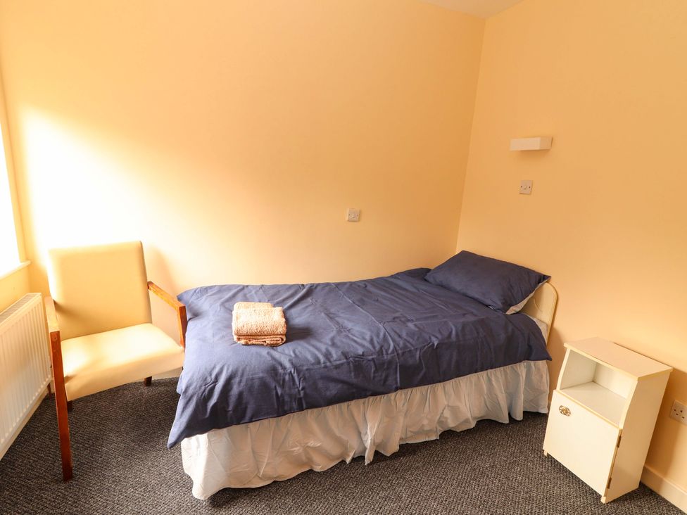 A bedroom with a bed and an armchair at Macmathuna, Kilrush, County Clare