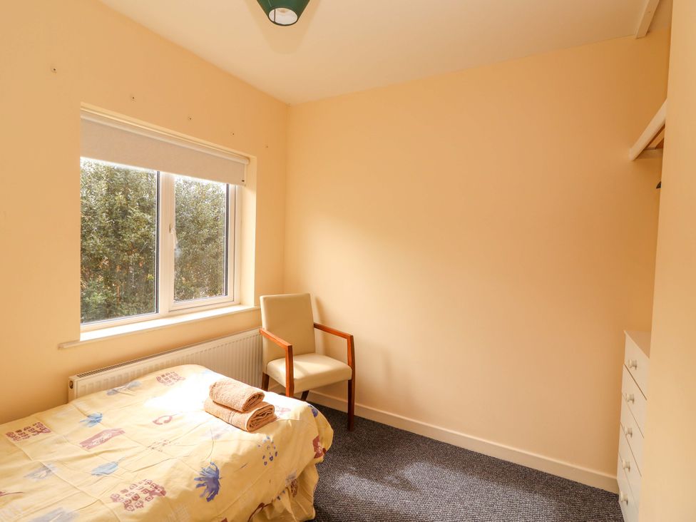 A bedroom with a bed and chair at Macmathuna in Kilrush, County Clare