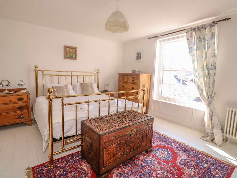 A bedroom with a brass bed and wooden chest at The Old Bank House in Mevagissey