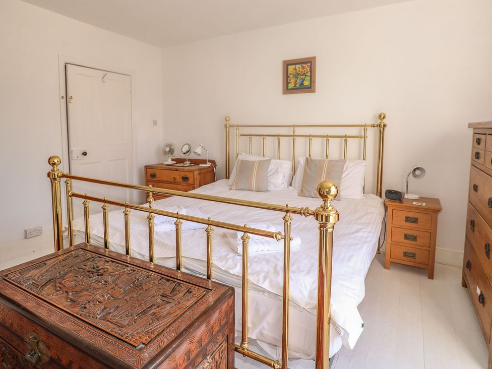 A bedroom with a brass bed and wooden furniture at The Old Bank House in Mevagissey