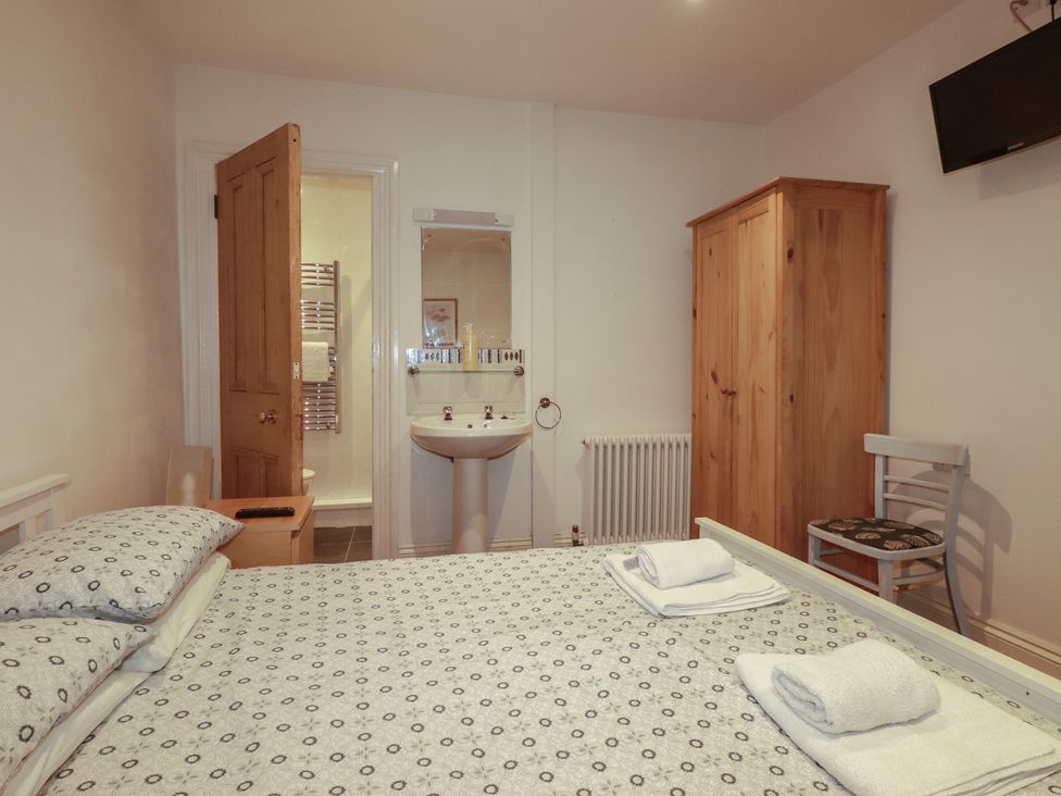 A bedroom with a bed and wardrobe at The Old Bank House in Mevagissey