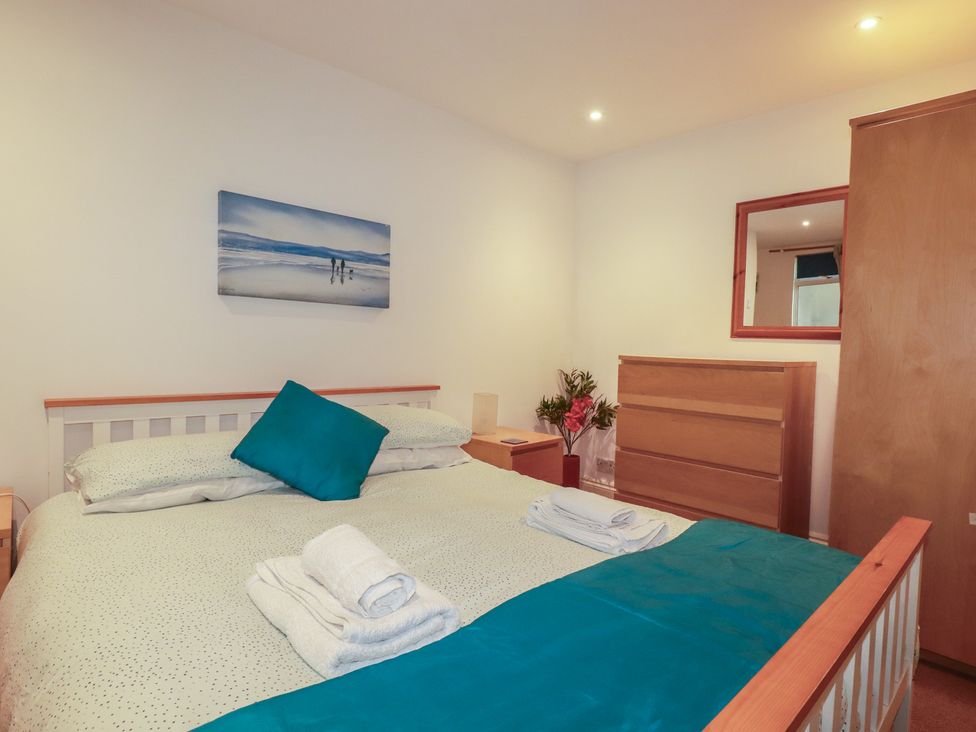 A bedroom with a bed, chest of drawers and wall art at The Old Bank House in Mevagissey