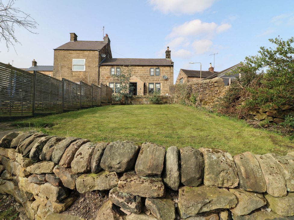 A garden with grass and a stone wall at 2 Knoll Mount in Matlock