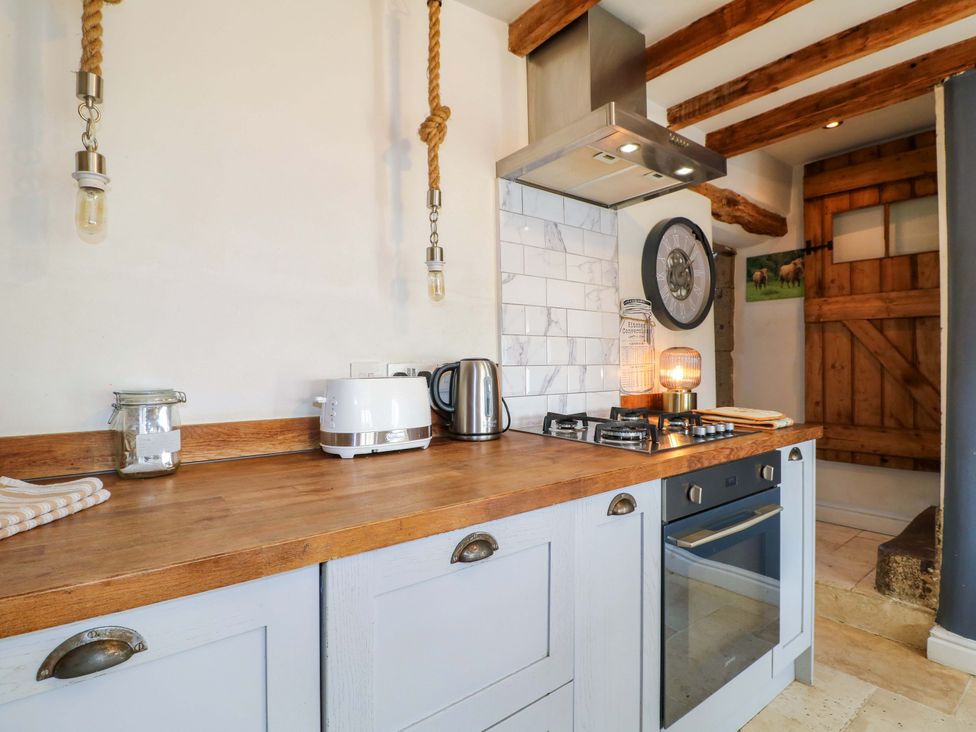 A kitchen with a wooden countertop, kettle, and gas cooker at 2 Knoll Mount, Matlock