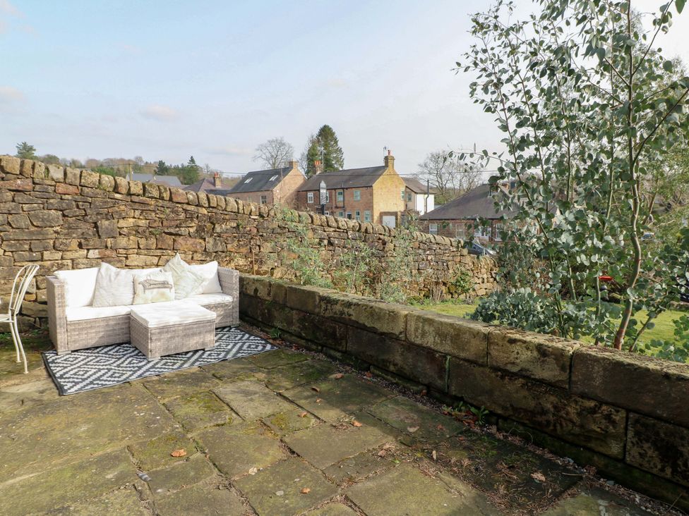 A garden with a stone wall and seating area at 2 Knoll Mount in Matlock