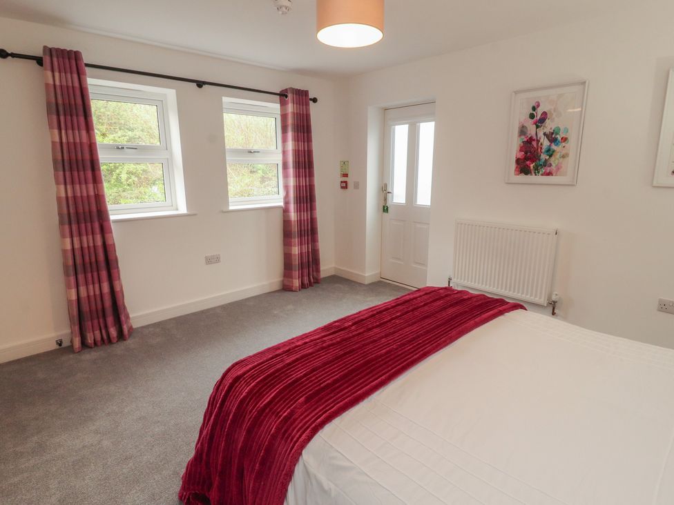 A bedroom with a bed and windows at Little Plum Tree in Milnthorpe