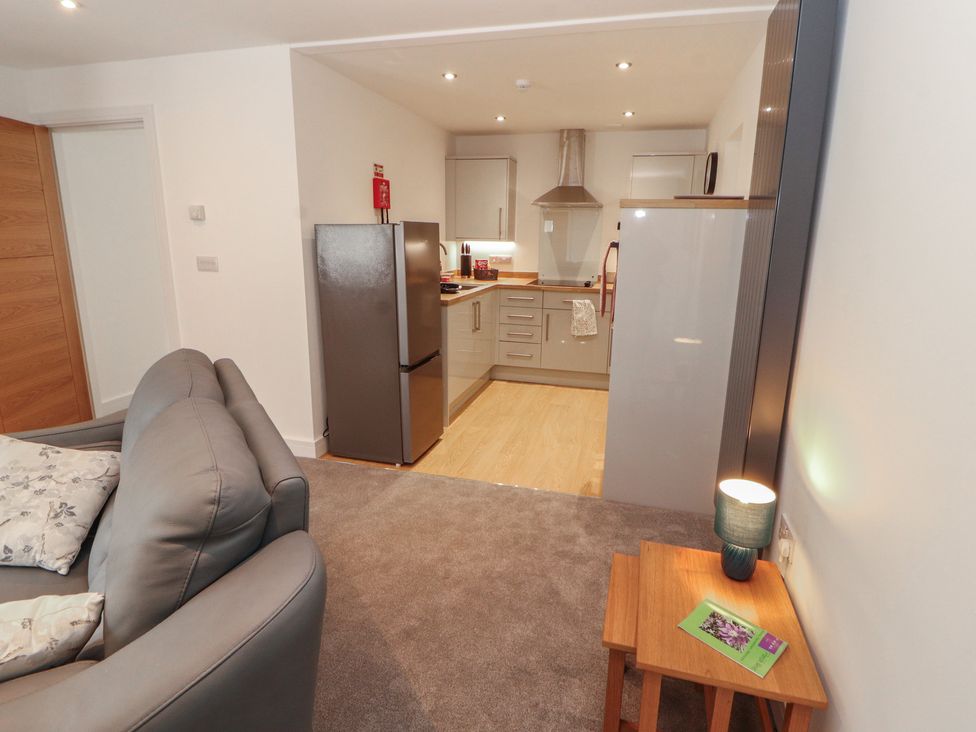 A living room with a sofa and kitchenette at Little Plumtree in Milnthorpe