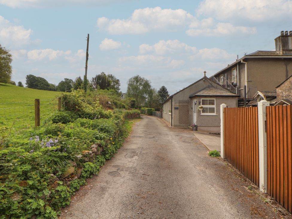 A road beside a building with a fence and garden at Little Plumtree in Milnthorpe