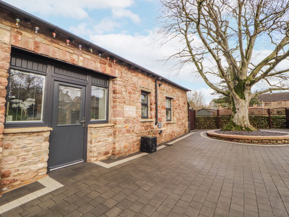 An outdoor view of a stone building with a patio at Blue Heron Lodge in Kirkby Stephen