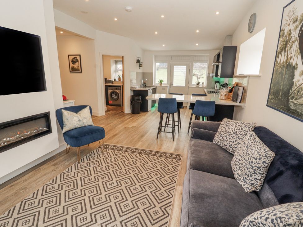 A living room with a sofa and kitchen area at Blue heron lodge in Kirkby Stephen